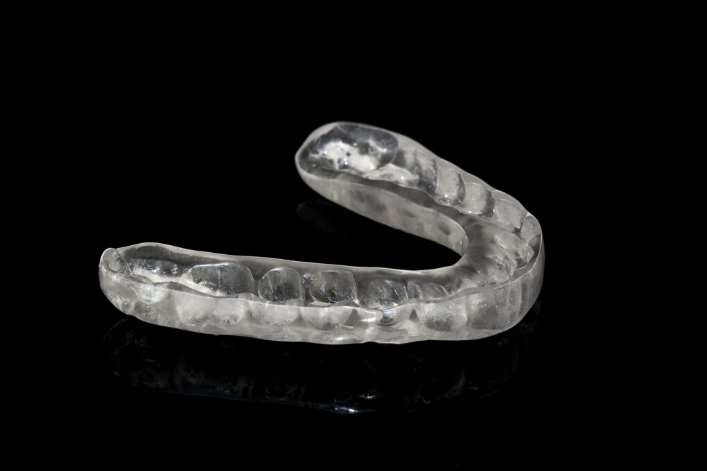 Acrylic transparent dental Mouth Guard on black background, showing reflection